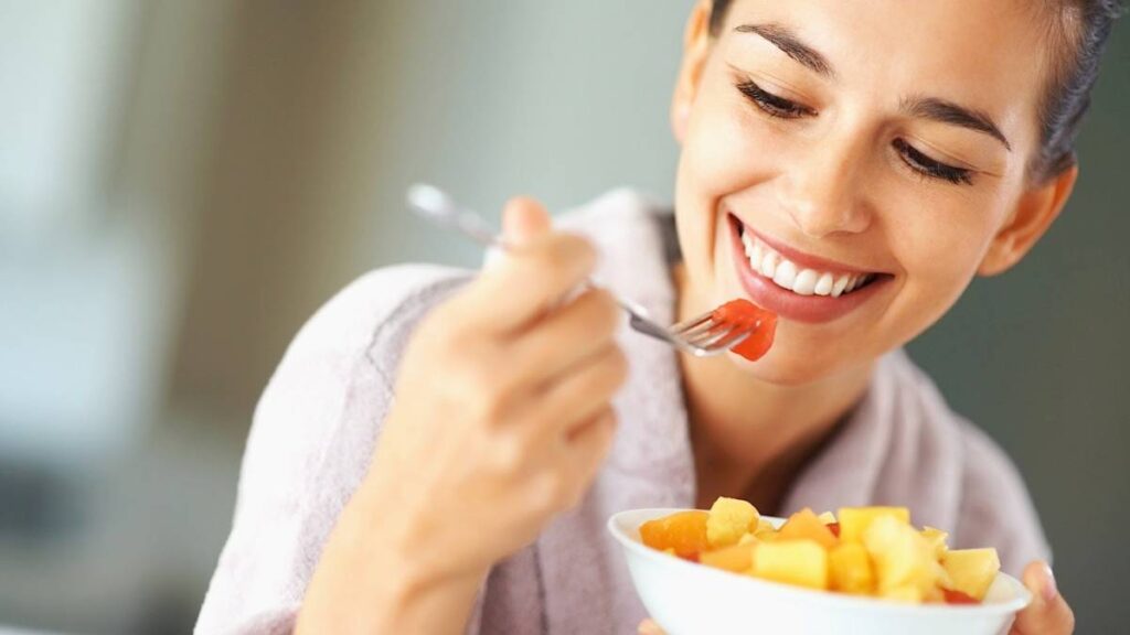 Mujer feliz y sin reflujo comiendo frutas