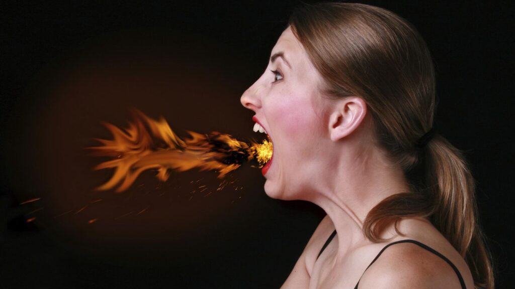 Mujer con reflujo expulsando fuego por la boca 