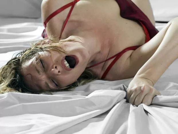 Mujer en la cama abriendo la boca de placer