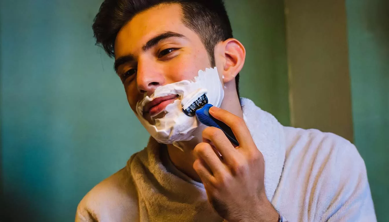 Hombre joven usando el rastrillo para afeitarse la cara